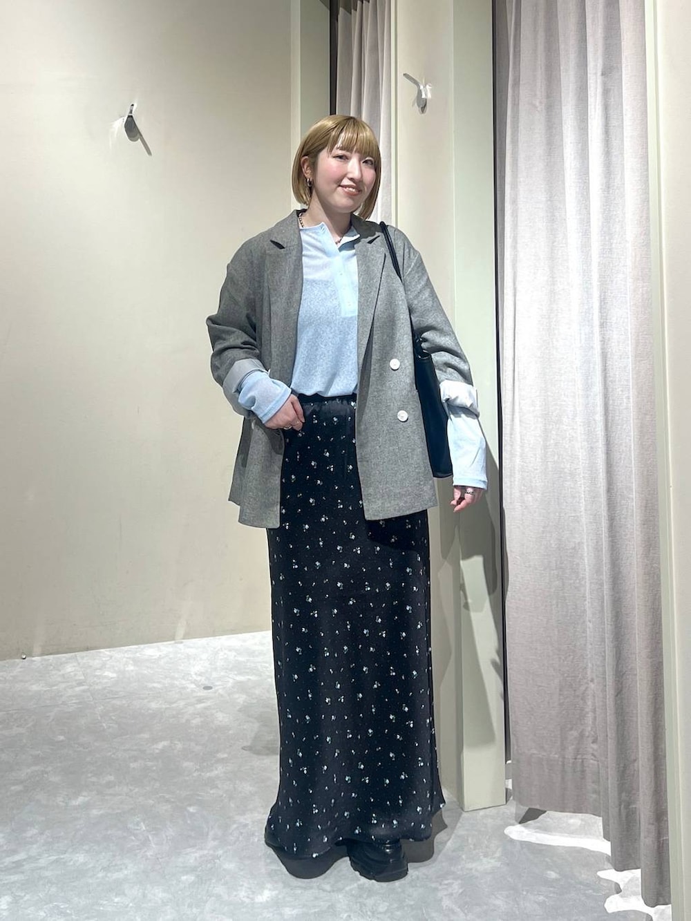 ブラック系のスカート、グレー系のテーラードジャケット、ブラック系のローファーを着用したレディースの春コーディネートの4枚目の写真