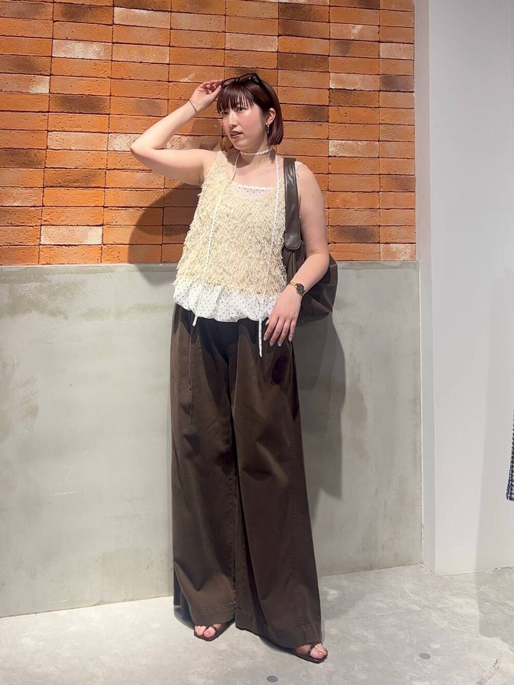 ブラウン系のショルダーバッグ、ブラウン系のサンダル、ホワイト系のベストを着用したレディースの夏コーディネートの4枚目の写真