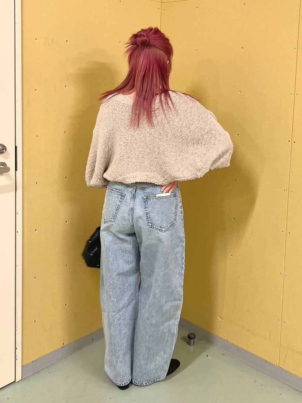 ブラック系のハンドバッグ、ブラック系のパンプス、ブルー系のデニムパンツを着用したレディースの春コーディネートの2枚目の写真