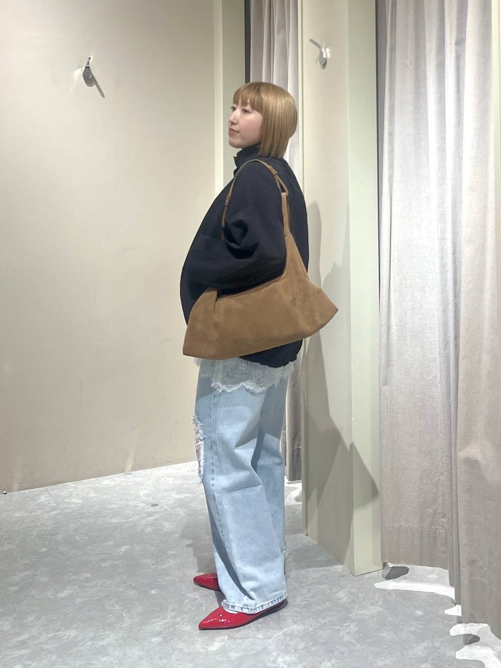 ブラック系のナイロンジャケット、レッド系のパンプス、ブルー系のデニムパンツを着用したレディースの春コーディネートの2枚目の写真