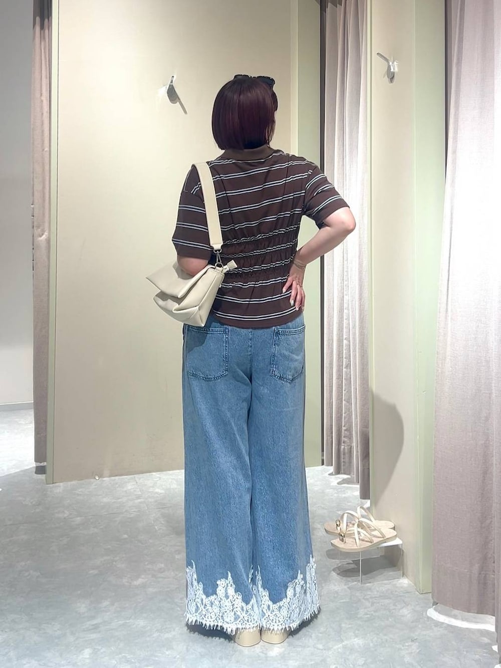 ホワイト系のショルダーバッグ、ブルー系のデニムパンツ、ホワイト系のサンダルを着用したレディースの夏コーディネートの2枚目の写真