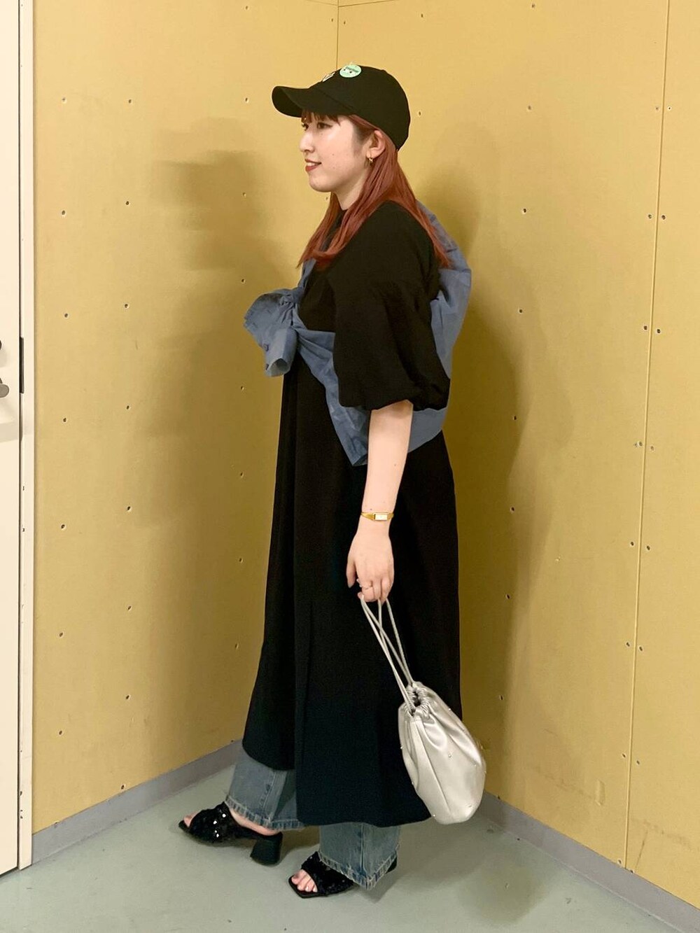 ブラック系のワンピース、シルバー系のショルダーバッグ、ブルー系のデニムパンツを着用したレディースの夏コーディネートの2枚目の写真