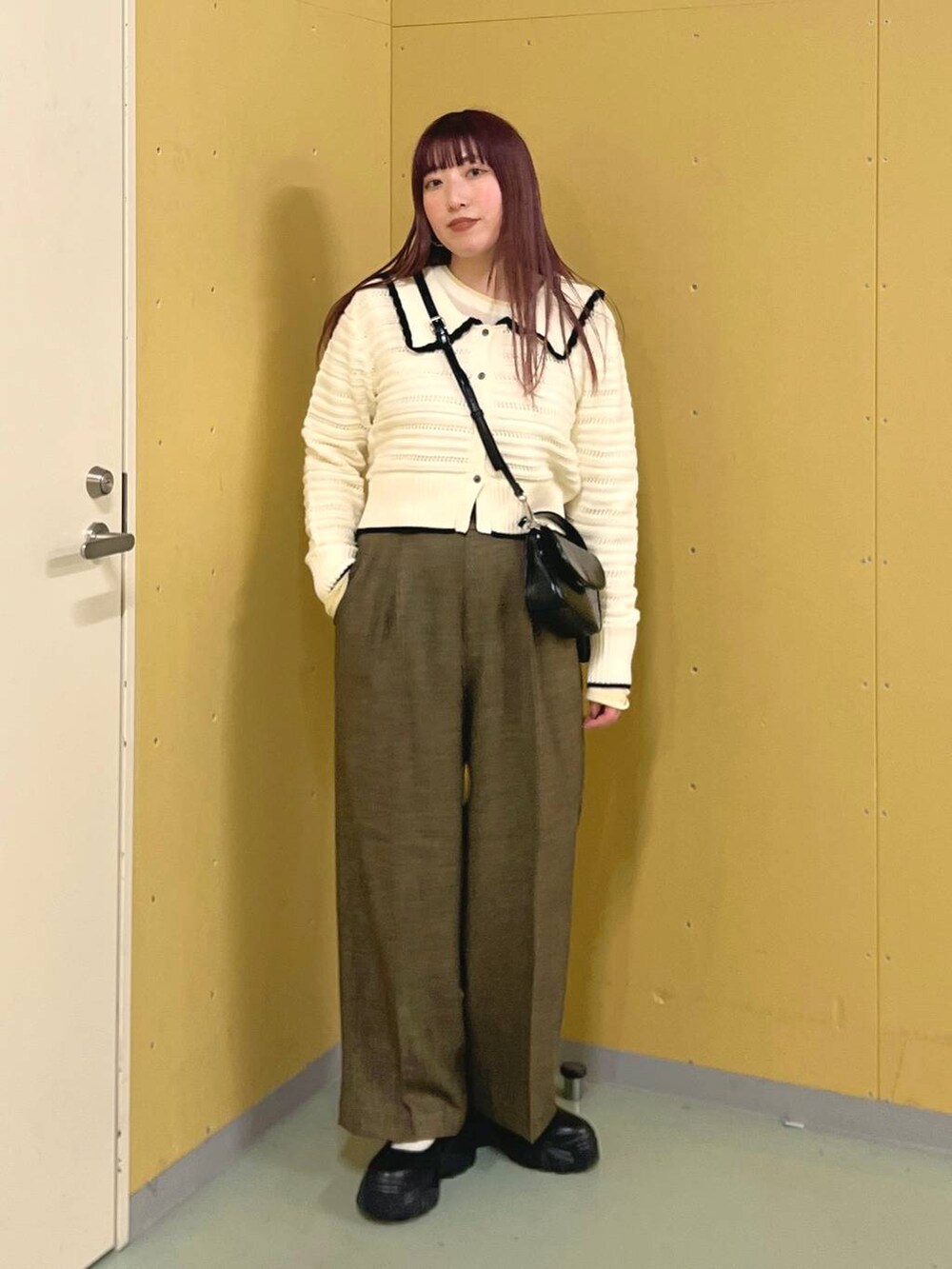 ブラック系のスニーカー、ブラウン系のスラックス、ブラック系のショルダーバッグを着用したレディースの冬コーディネートの3枚目の写真