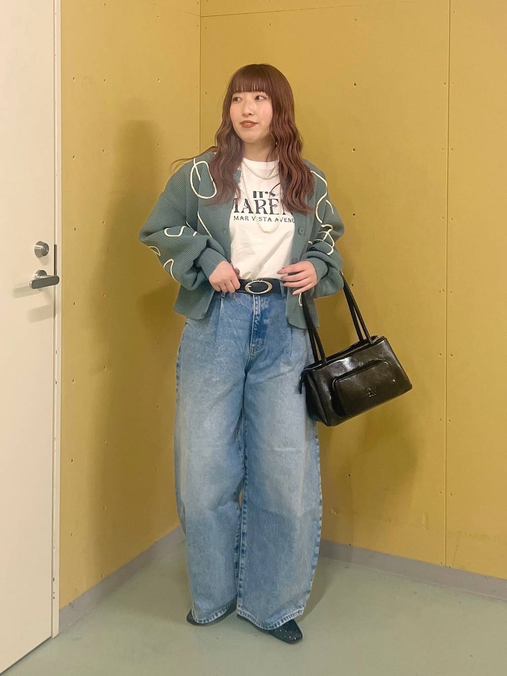 ブラック系のショルダーバッグ、ブルー系のデニムパンツ、ブルー系のカーディガン/ボレロを着用したレディースの冬コーディネートの2枚目の写真