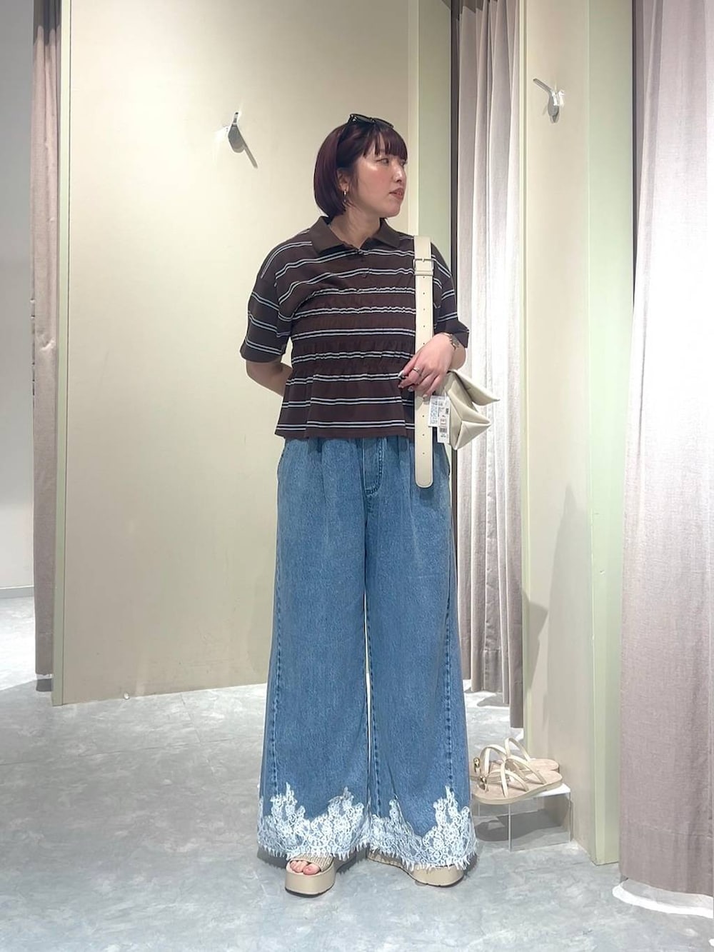 ホワイト系のショルダーバッグ、ブルー系のデニムパンツ、ホワイト系のサンダルを着用したレディースの夏コーディネートの3枚目の写真