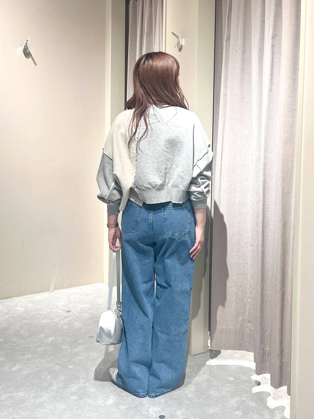 グレー系のスウェット、ブルー系のデニムパンツ、シルバー系のトートバッグを着用したレディースの春コーディネートの3枚目の写真