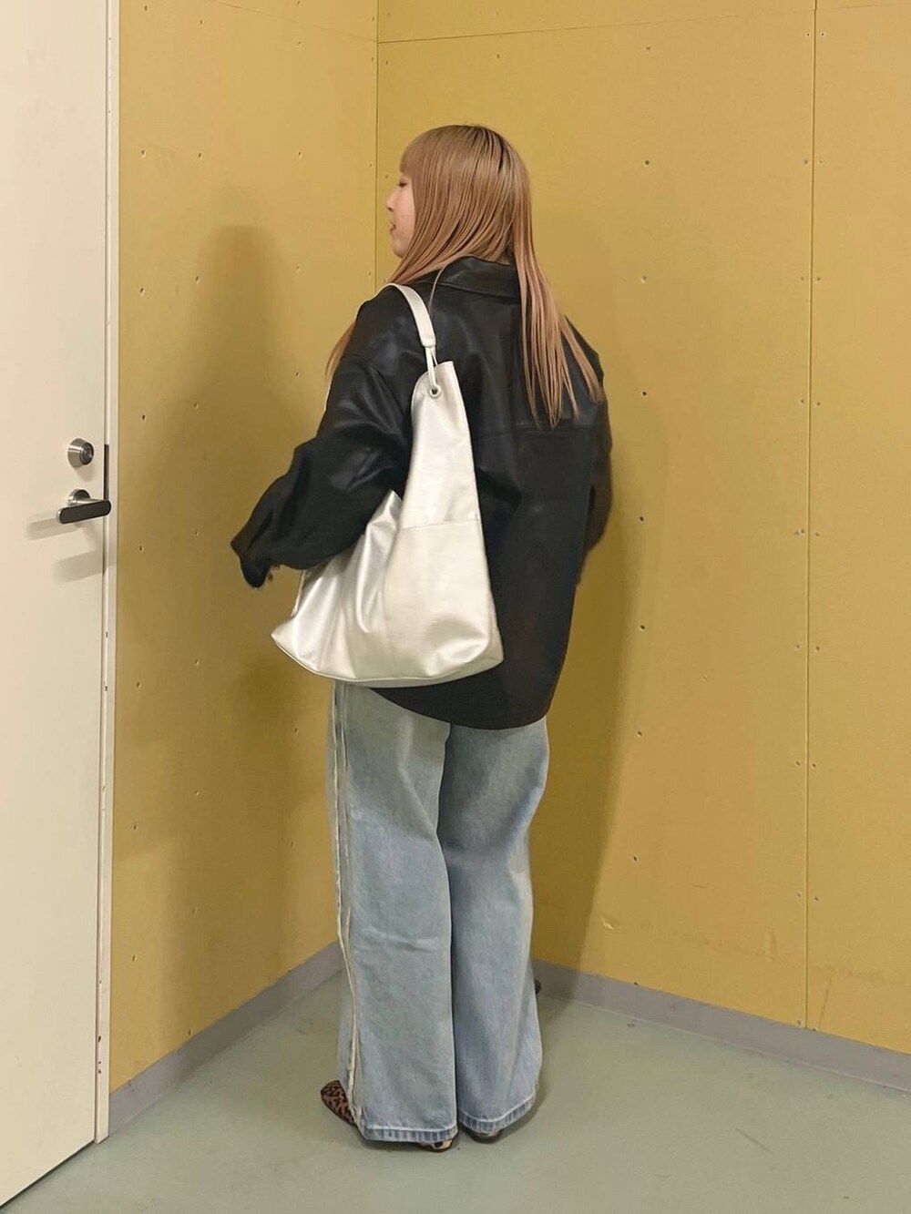 ブルー系のデニムパンツ、ブラウン系のバレエシューズ、シルバー系のトートバッグを着用したレディースの冬コーディネートの2枚目の写真