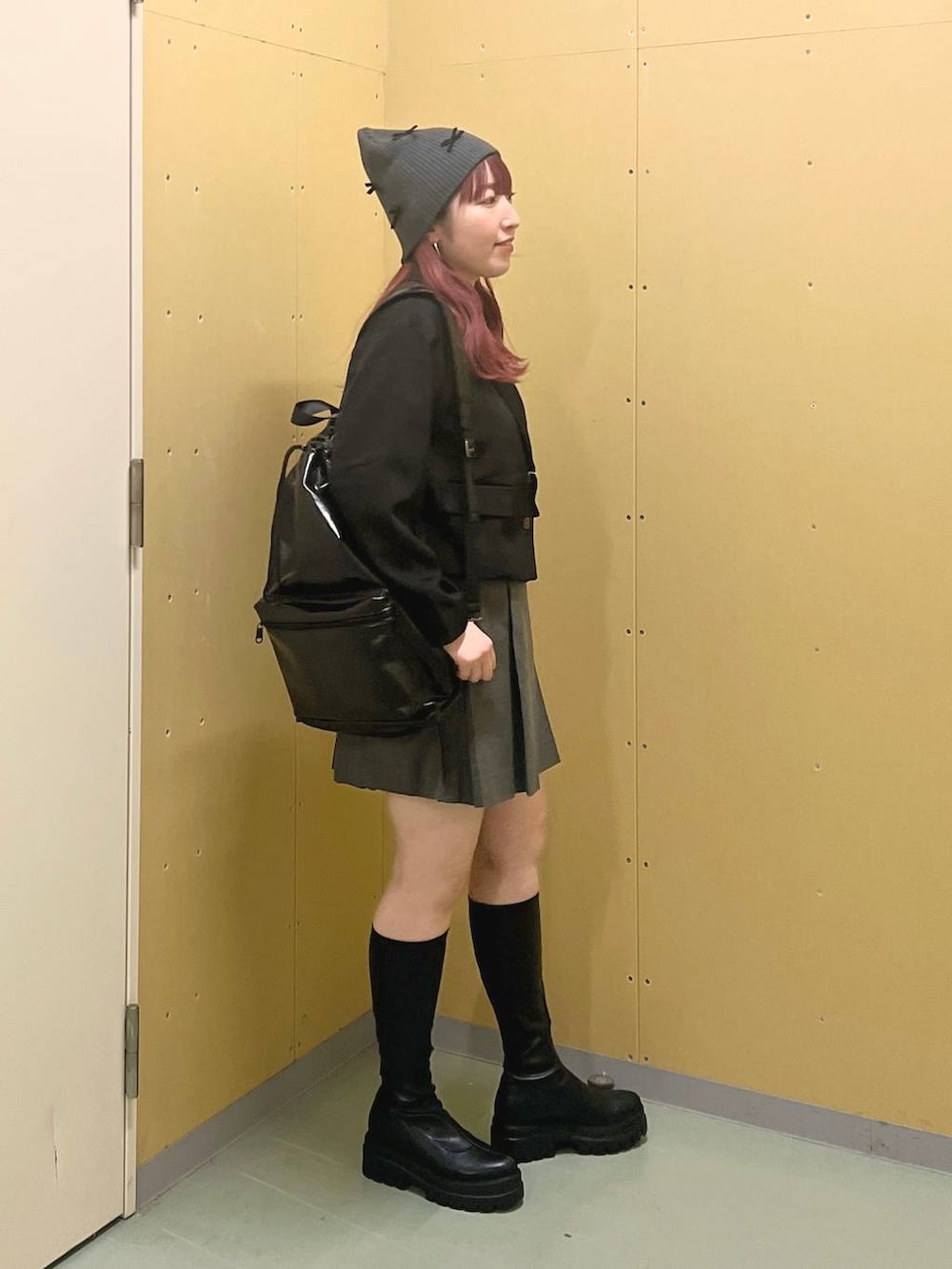 ブラック系のショルダーバッグ、グレー系のスカート、ブラック系のブーツを着用したレディースの秋コーディネートの2枚目の写真