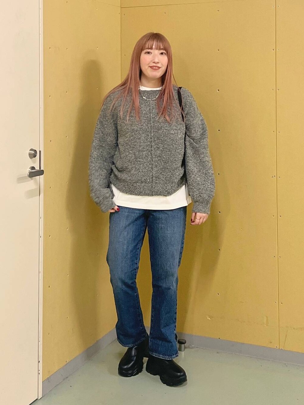 ブルー系のデニムパンツ、ブラック系のブーツ、ホワイト系のTシャツ/カットソーを着用したレディースの冬コーディネートの4枚目の写真