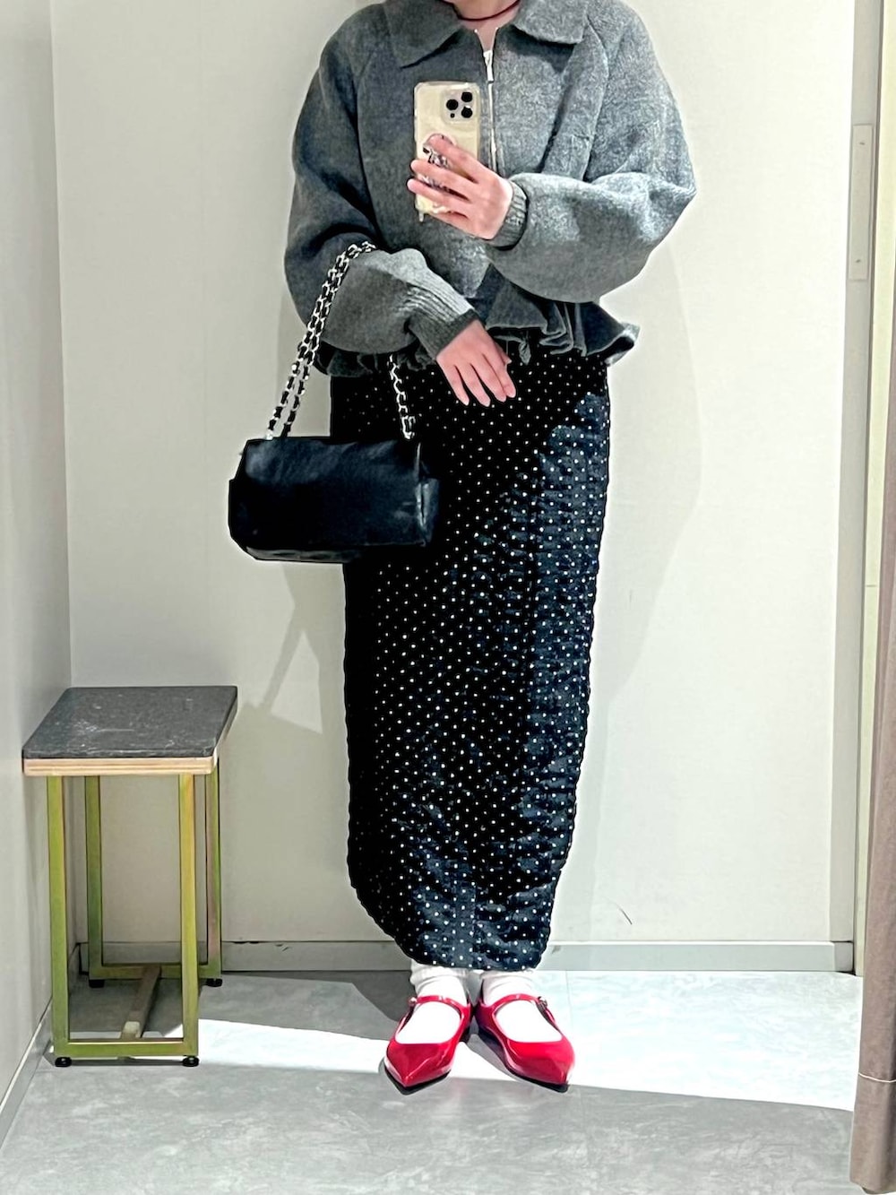 レッド系のパンプス、ブラック系のショルダーバッグ、ブラック系のスカートを着用したレディースの冬コーディネートの5枚目の写真