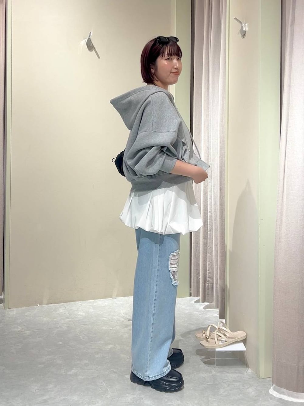 グレー系のパーカー、ブルー系のデニムパンツ、ブラック系のローファーを着用したレディースの秋コーディネートの2枚目の写真