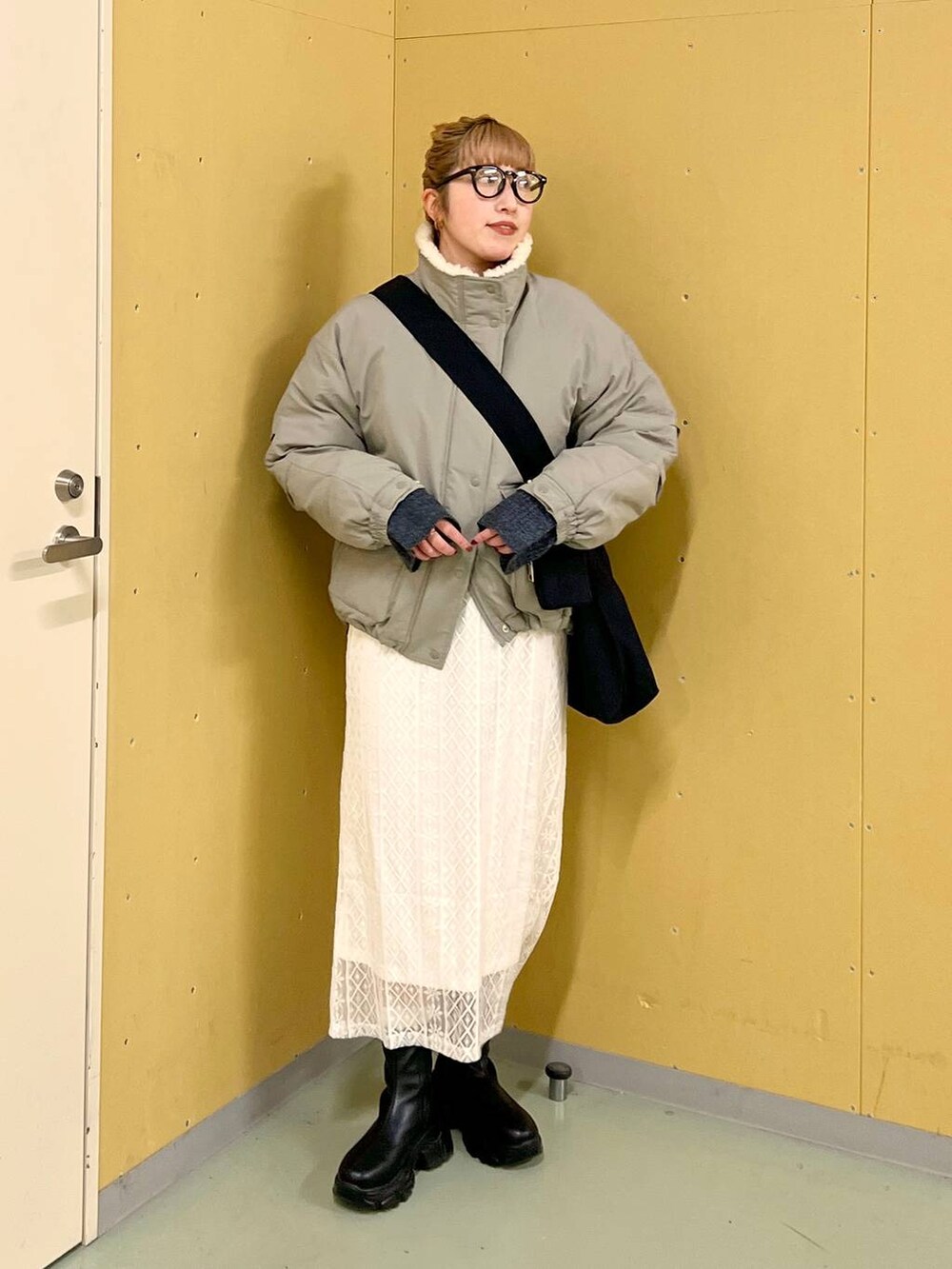 ブラック系のブーツ、ブルー系のワンピース、グリーン系のブルゾンを着用したレディースの冬コーディネートの4枚目の写真