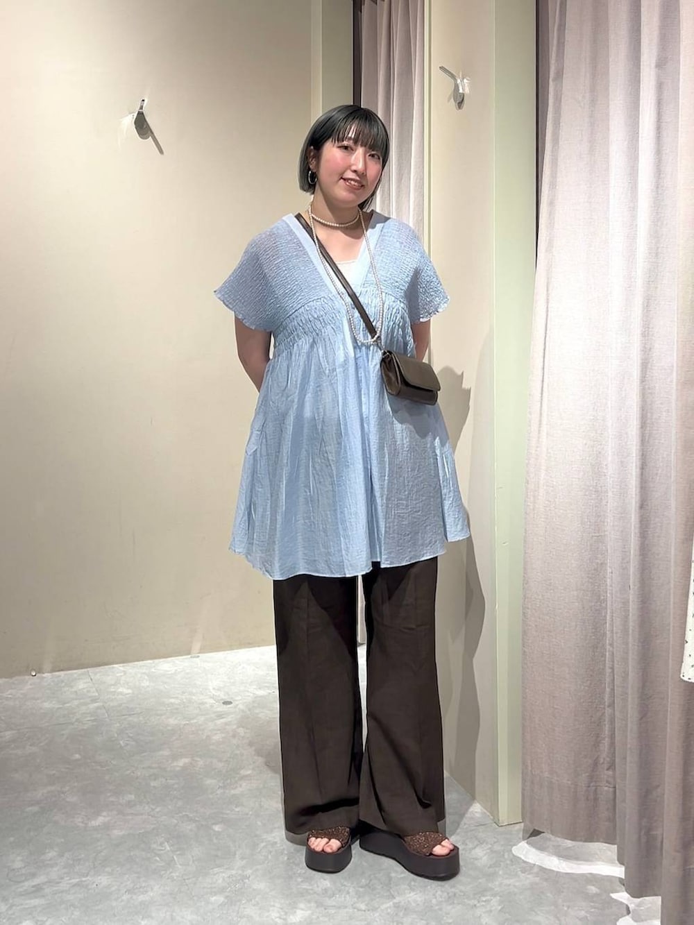 シルバー系のタンクトップ、ブルー系のシャツ/ブラウス、ブラウン系のスラックスを着用したレディースの春コーディネートの4枚目の写真