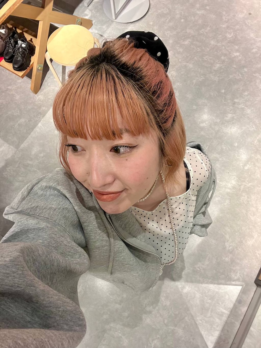 レッド系のパンプス、グレー系のパーカー、ブルー系のデニムパンツを着用したレディースの春コーディネートの4枚目の写真