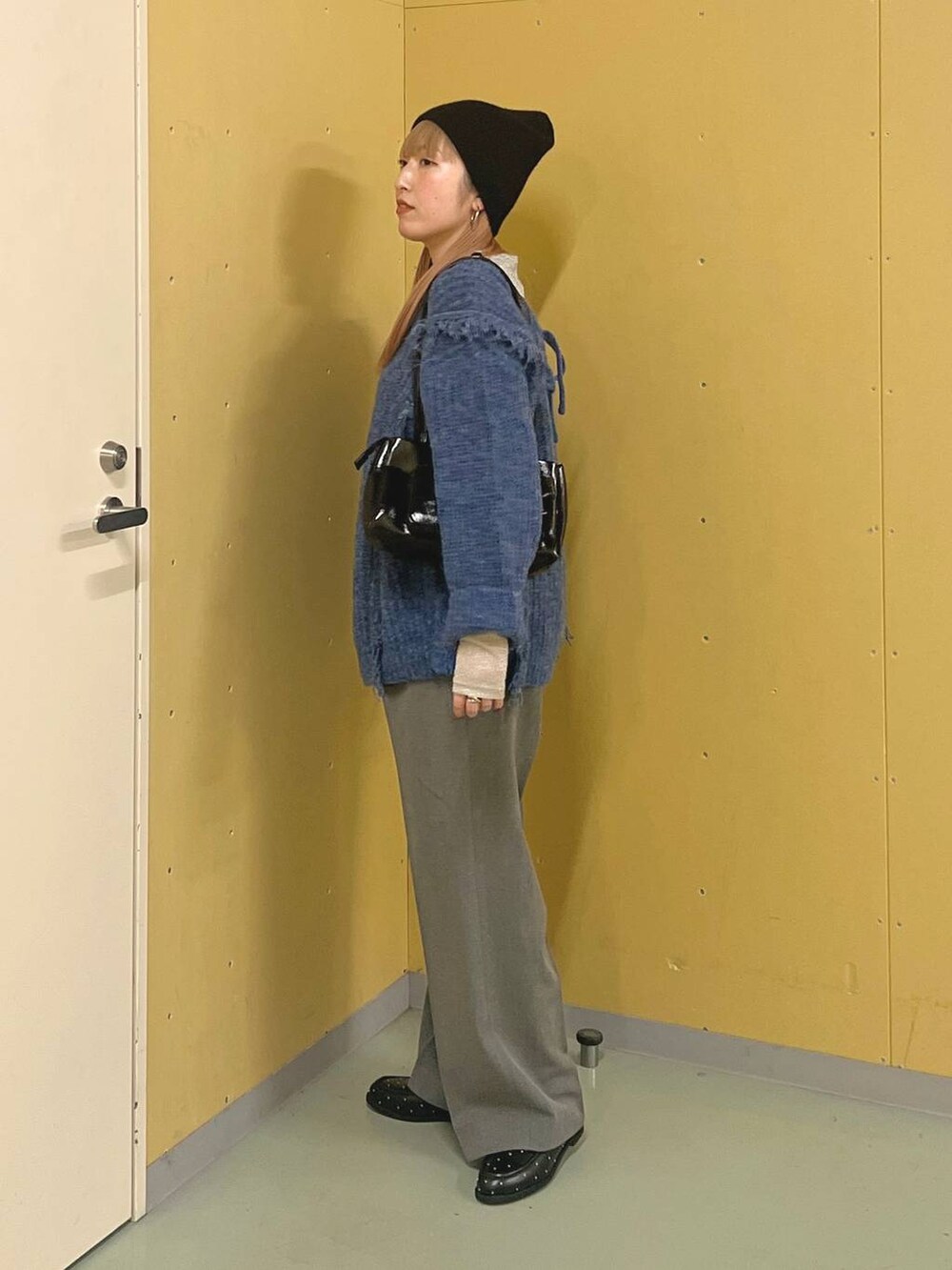 ブルー系のニット/セーター、ブラック系のショルダーバッグ、シルバー系のTシャツ/カットソーを着用したレディースの冬コーディネートの2枚目の写真