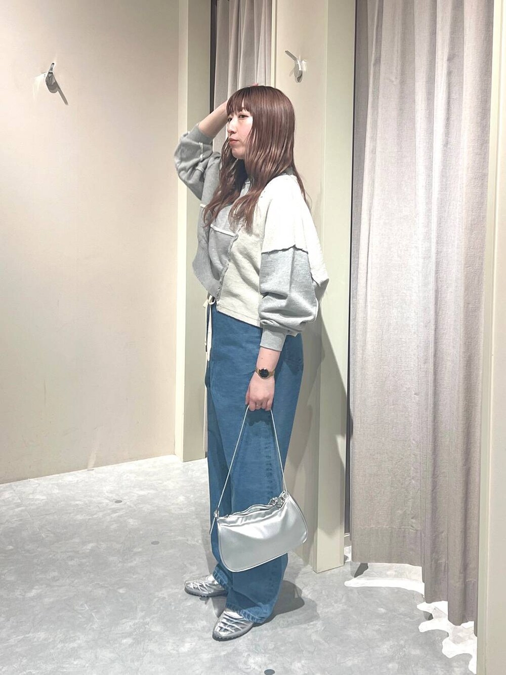 グレー系のスウェット、ブルー系のデニムパンツ、シルバー系のトートバッグを着用したレディースの春コーディネートの2枚目の写真