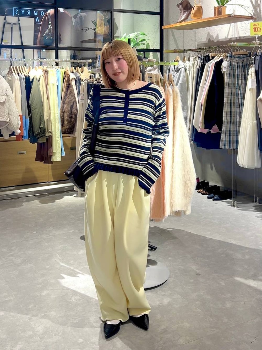 イエロー系のスウェットパンツ、ブラック系のパンプス、ブラウン系のショルダーバッグを着用したレディースの冬コーディネートの6枚目の写真