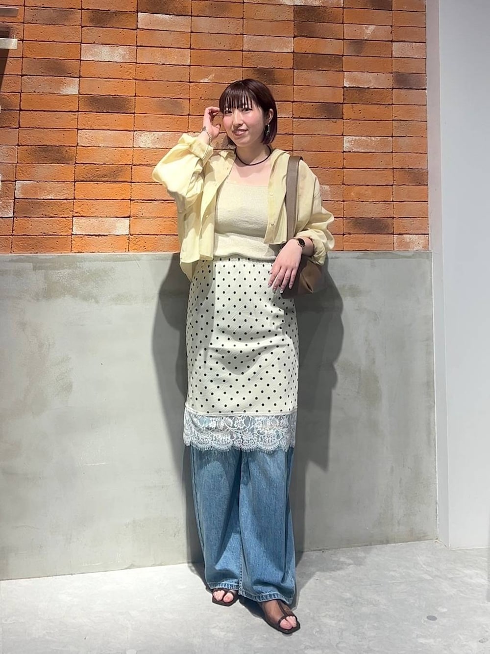 ゴールド系のタンクトップ、イエロー系のシャツ/ブラウス、ブルー系のデニムパンツを着用したレディースの夏コーディネートの2枚目の写真