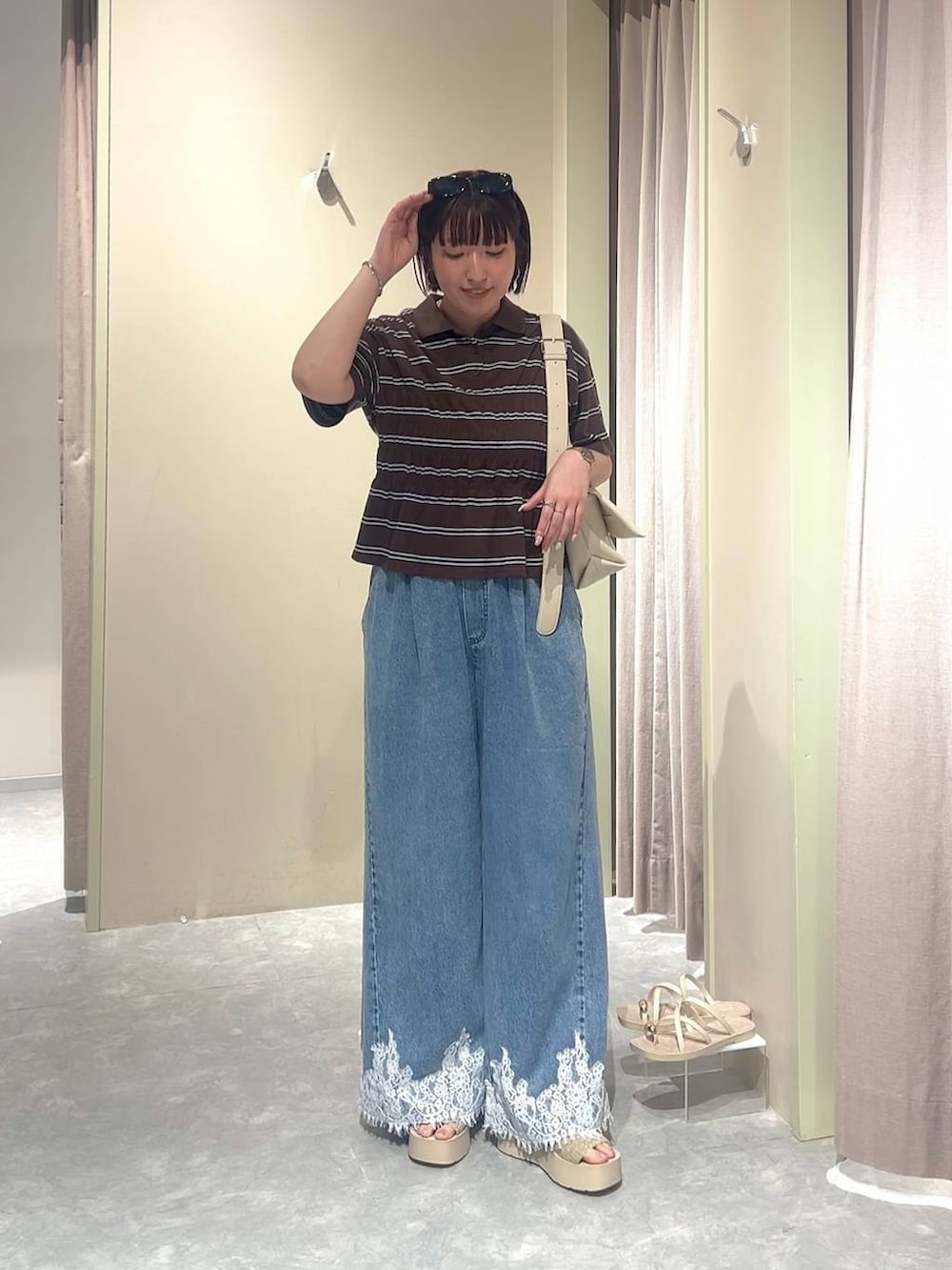 ホワイト系のショルダーバッグ、ブルー系のデニムパンツ、ホワイト系のサンダルを着用したレディースの夏コーディネートの4枚目の写真