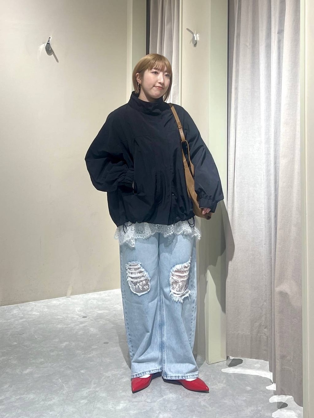 ブラック系のナイロンジャケット、レッド系のパンプス、ブルー系のデニムパンツを着用したレディースの春コーディネートの4枚目の写真