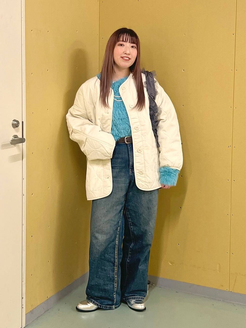 ホワイト系のブルゾン、ブルー系のデニムパンツ、シルバー系のローファーを着用したレディースの冬コーディネートの4枚目の写真