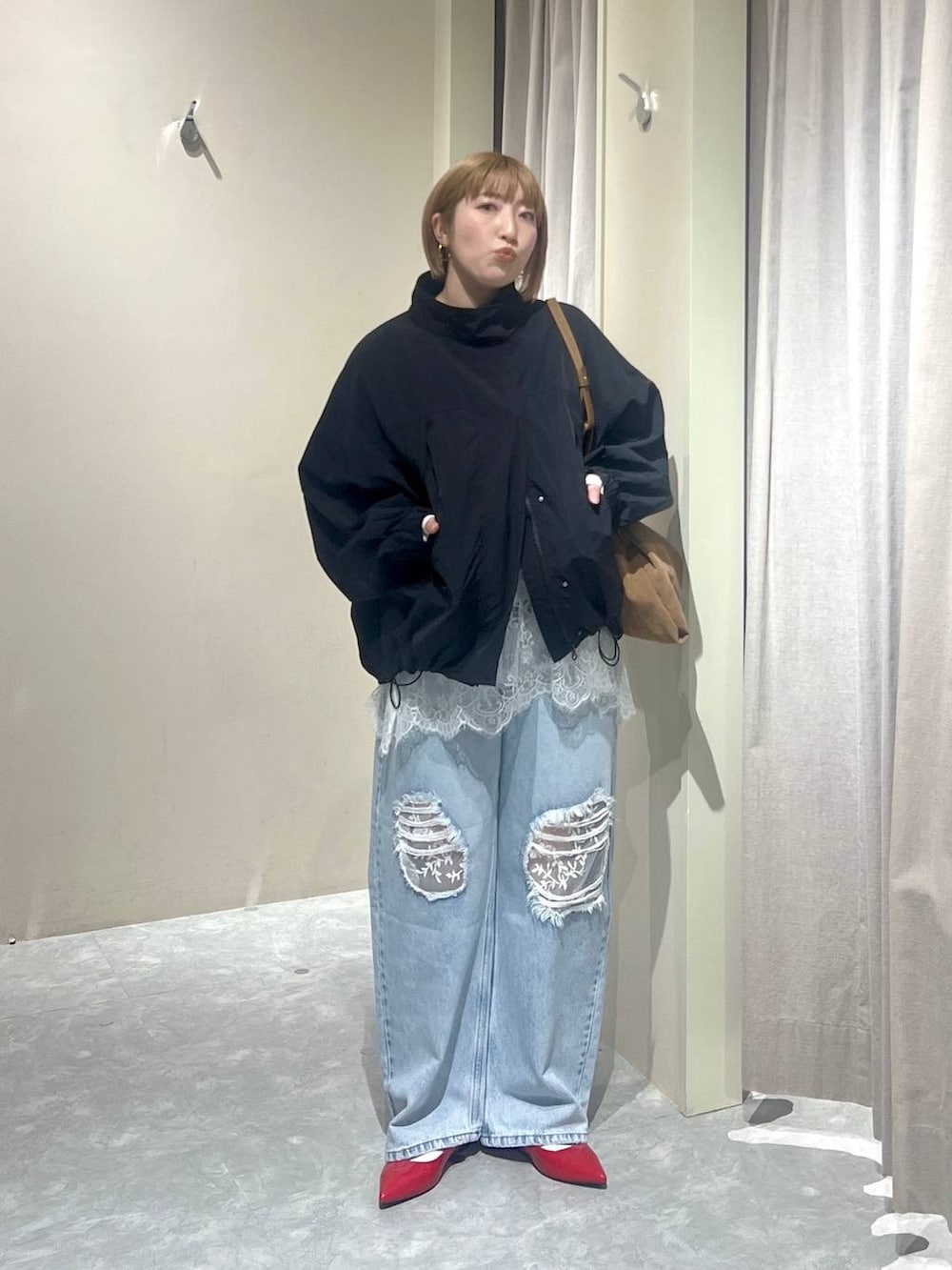 ブラック系のナイロンジャケット、レッド系のパンプス、ブルー系のデニムパンツを着用したレディースの春コーディネートの6枚目の写真