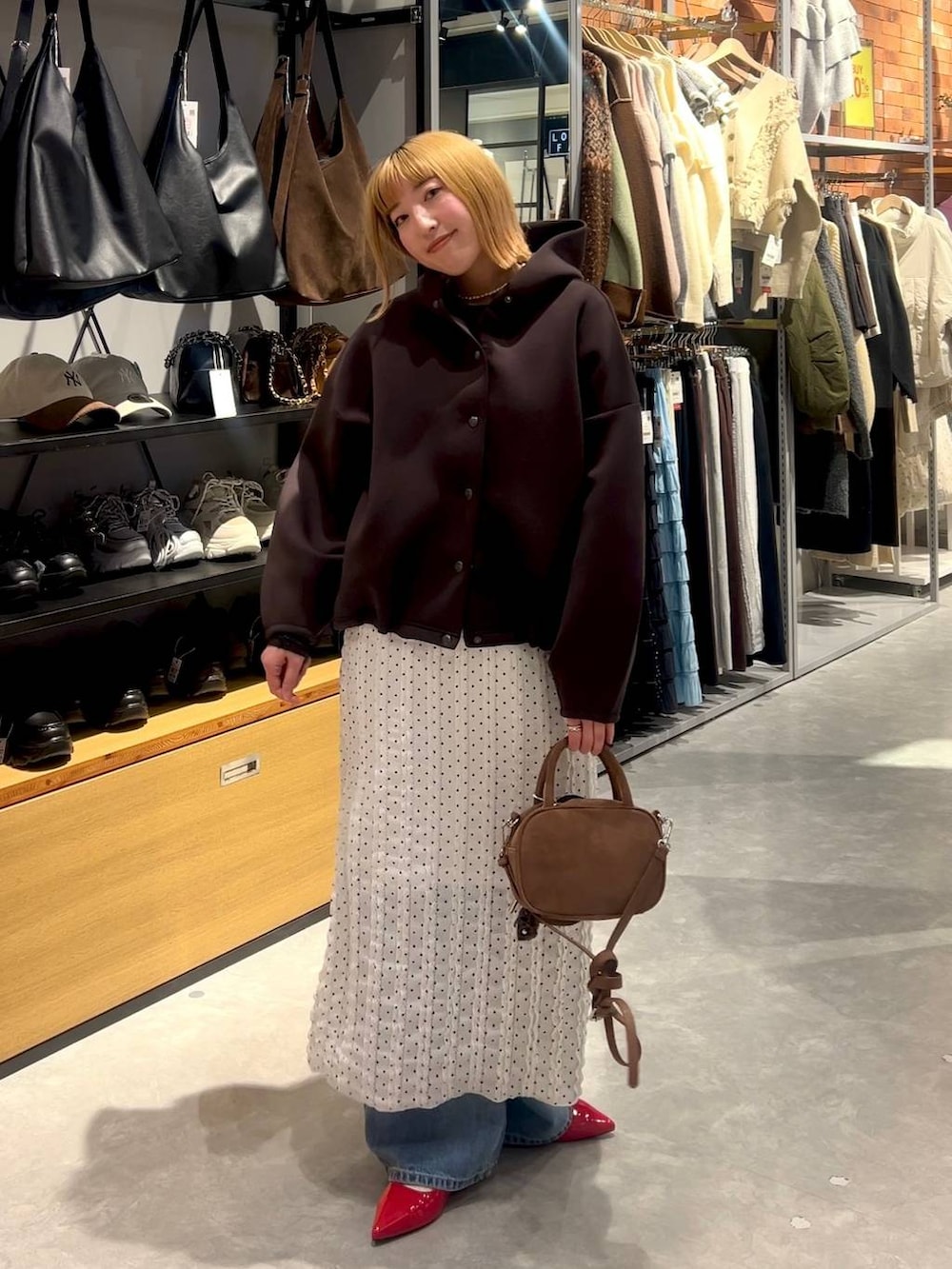 レッド系のパンプス、ブラウン系のボストンバッグ、ブルー系のデニムパンツを着用したレディースの春コーディネートの5枚目の写真