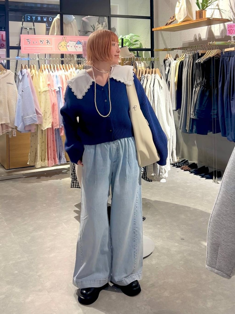 ブラック系のサンダル、ブルー系のデニムパンツ、ホワイト系のショルダーバッグを着用したレディースの冬コーディネートの7枚目の写真