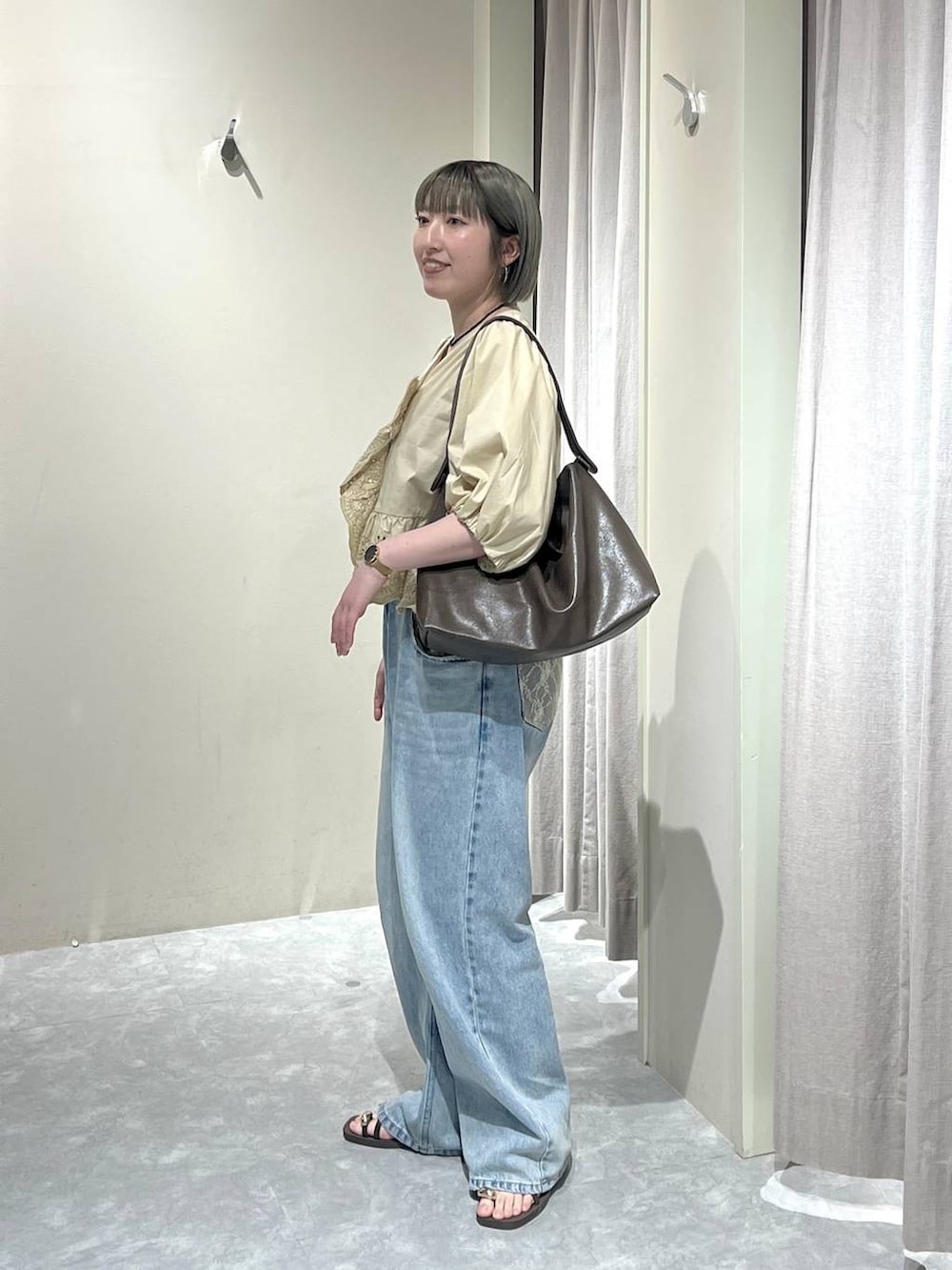 ブルー系のデニムパンツ、ブラウン系のサンダル、ベージュ系のシャツ/ブラウスを着用したレディースの春コーディネートの2枚目の写真