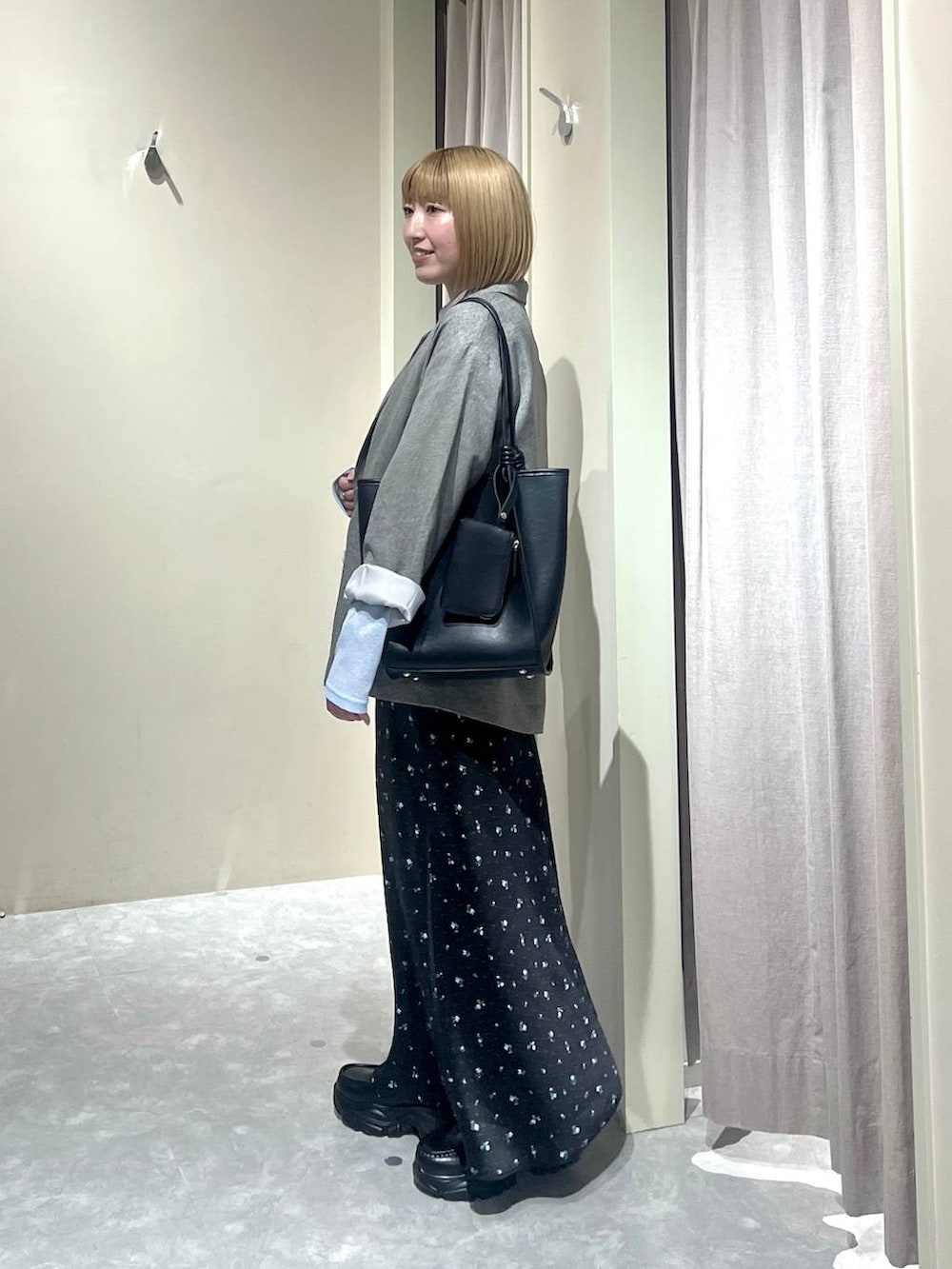 ブラック系のスカート、グレー系のテーラードジャケット、ブラック系のローファーを着用したレディースの春コーディネートの2枚目の写真