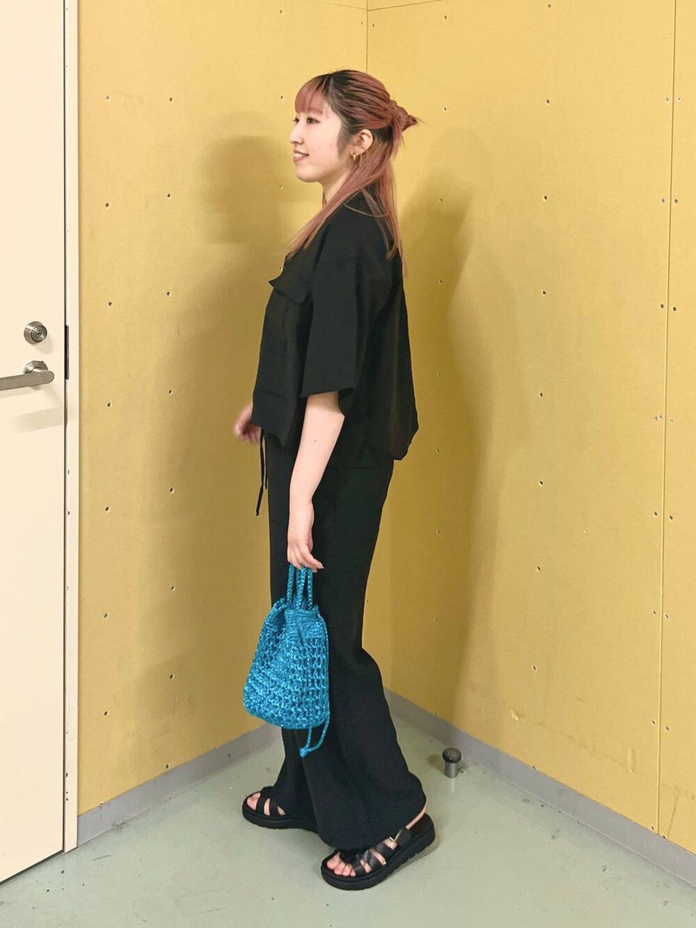 ブラック系のスニーカー、ホワイト系のTシャツ/カットソー、ブルー系のショルダーバッグを着用したレディースの春コーディネートの2枚目の写真