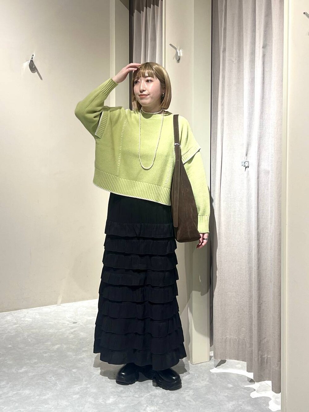 ブラウン系のショルダーバッグ、ブラック系のブーツ、グリーン系のニット/セーターを着用したレディースの冬コーディネートの4枚目の写真