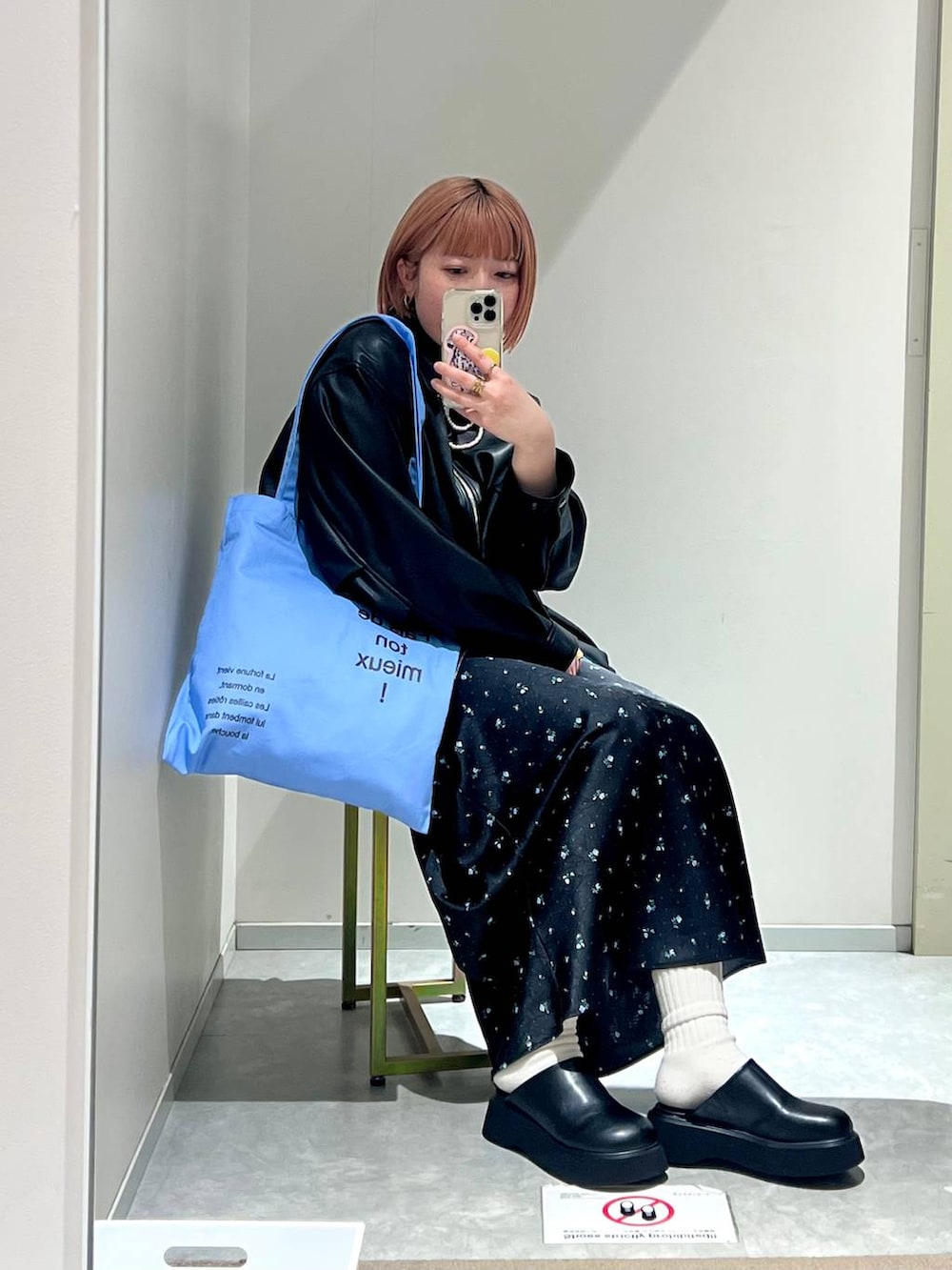 ブラック系のスカート、ブラック系のサンダル、ブルー系のトートバッグを着用したレディースの冬コーディネートの7枚目の写真