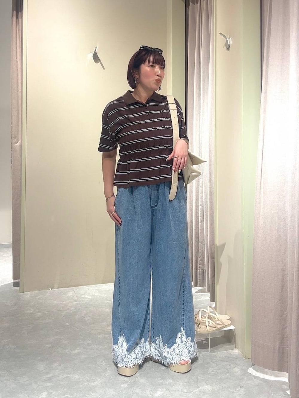 ホワイト系のショルダーバッグ、ブルー系のデニムパンツ、ホワイト系のサンダルを着用したレディースの夏コーディネートの5枚目の写真