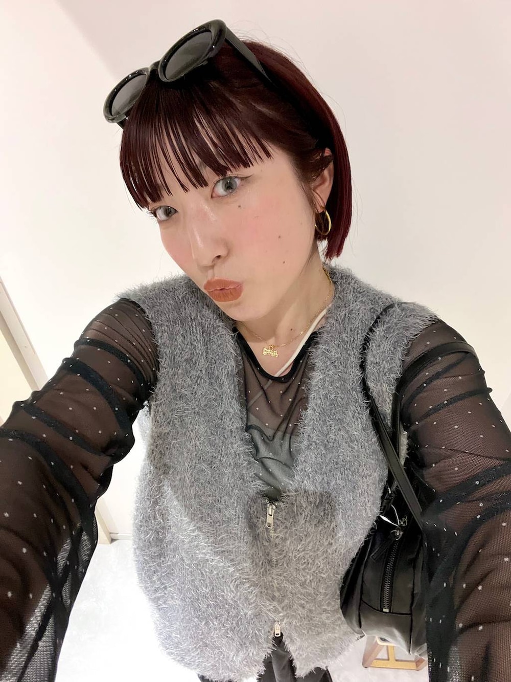 ブラック系のブーツ、ブラック系のボストンバッグ、グレー系のベストを着用したレディースの秋コーディネートの9枚目の写真