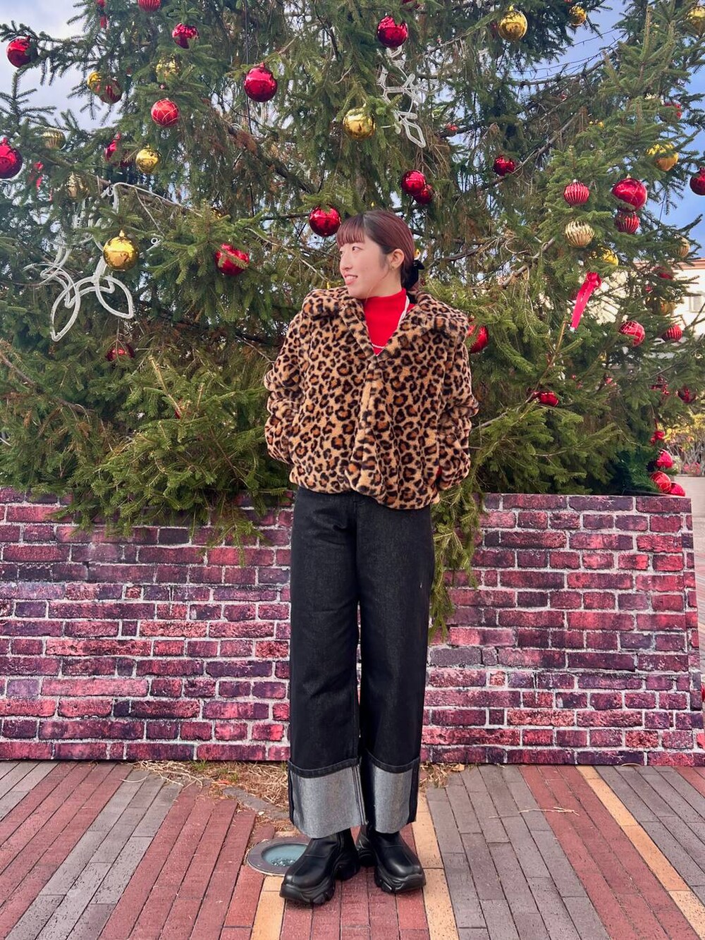 レッド系のニット/セーター、ブラック系のブーツ、その他のブルゾンを着用したレディースの冬コーディネートの2枚目の写真