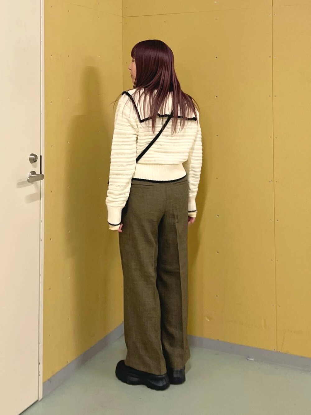 ブラック系のスニーカー、ブラウン系のスラックス、ブラック系のショルダーバッグを着用したレディースの冬コーディネートの2枚目の写真