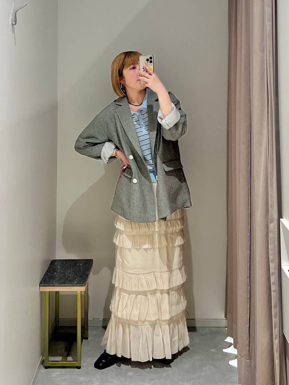 グレー系のテーラードジャケット、ホワイト系のスカート、ブルー系のポロシャツを着用したレディースの春コーディネートの3枚目の写真