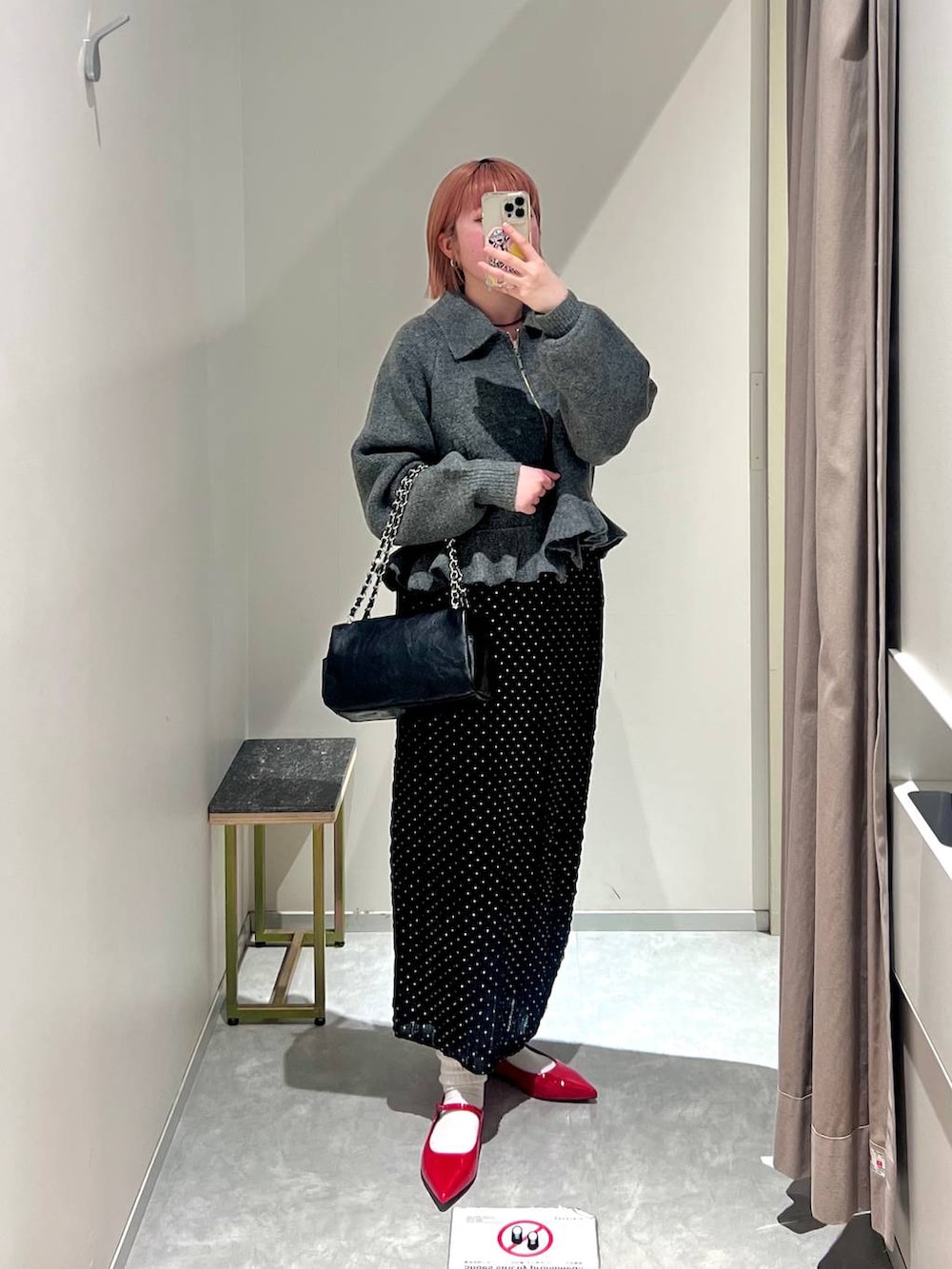 レッド系のパンプス、ブラック系のショルダーバッグ、ブラック系のスカートを着用したレディースの冬コーディネートの6枚目の写真