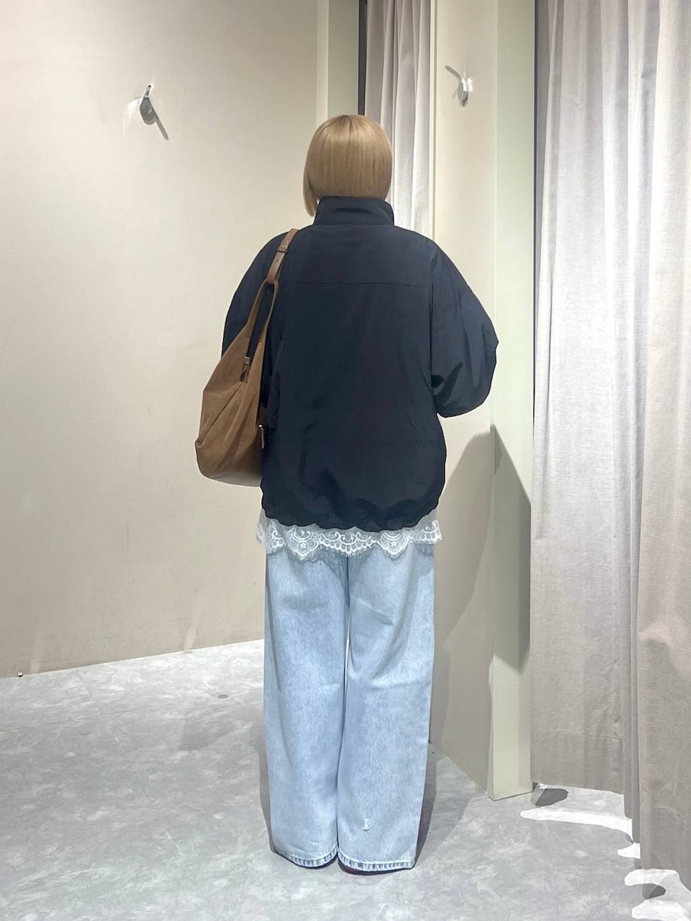 ブラック系のナイロンジャケット、レッド系のパンプス、ブルー系のデニムパンツを着用したレディースの春コーディネートの3枚目の写真