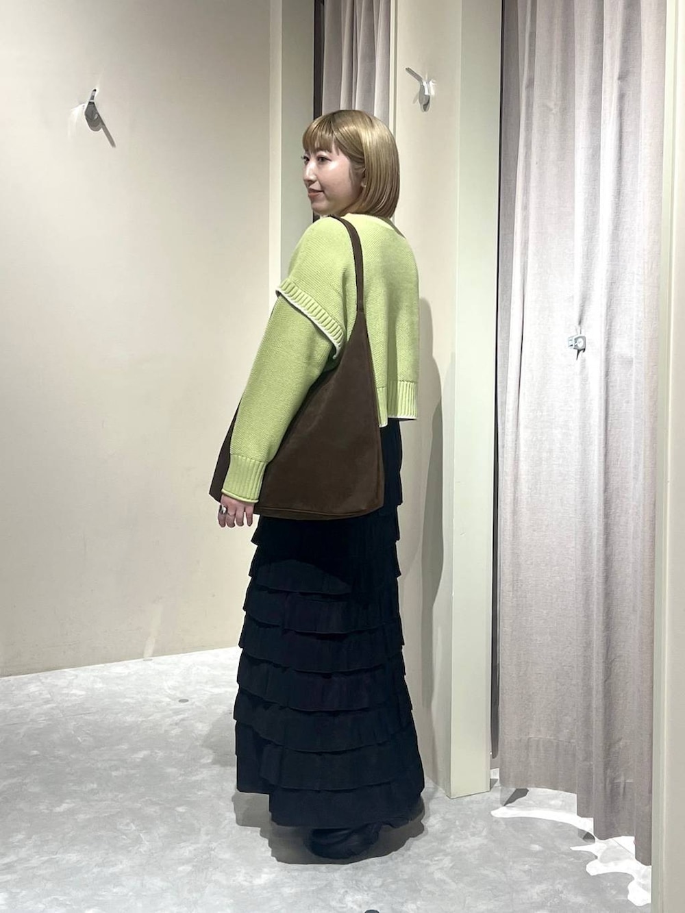 ブラウン系のショルダーバッグ、ブラック系のブーツ、グリーン系のニット/セーターを着用したレディースの冬コーディネートの2枚目の写真