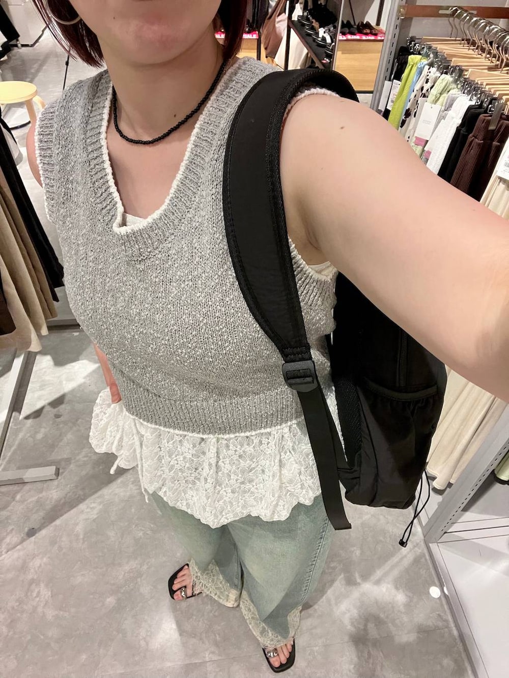 ブルー系のデニムパンツ、ブラック系のサンダル、グレー系のベストを着用したレディースの夏コーディネートの4枚目の写真
