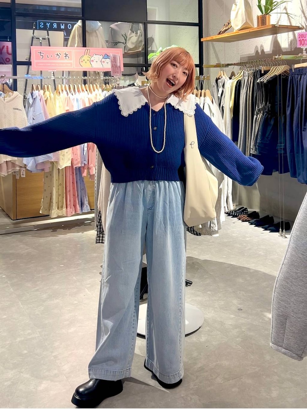 ブラック系のサンダル、ブルー系のデニムパンツ、ホワイト系のショルダーバッグを着用したレディースの冬コーディネートの5枚目の写真