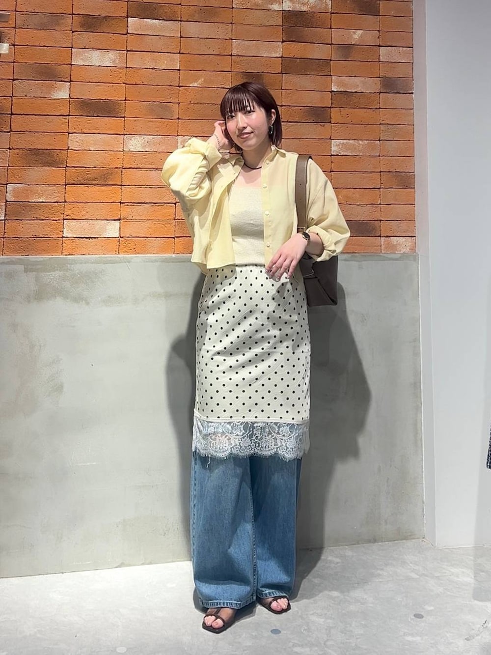 ゴールド系のタンクトップ、イエロー系のシャツ/ブラウス、ブルー系のデニムパンツを着用したレディースの夏コーディネートの5枚目の写真