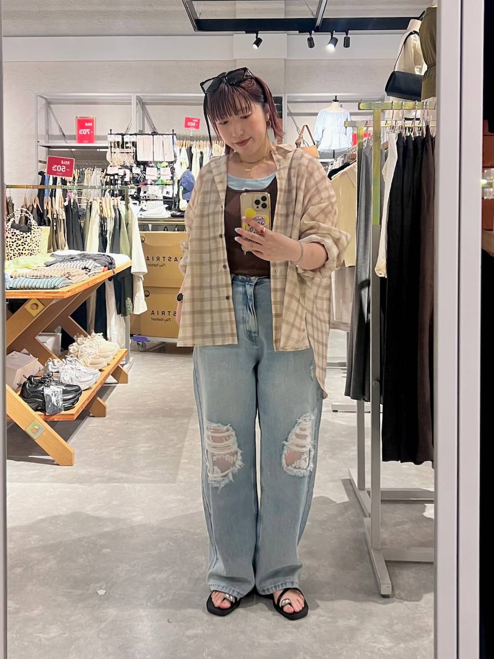 ブルー系のデニムパンツ、ベージュ系のシャツ/ブラウス、ブラック系のサンダルを着用したレディースの夏コーディネートの2枚目の写真