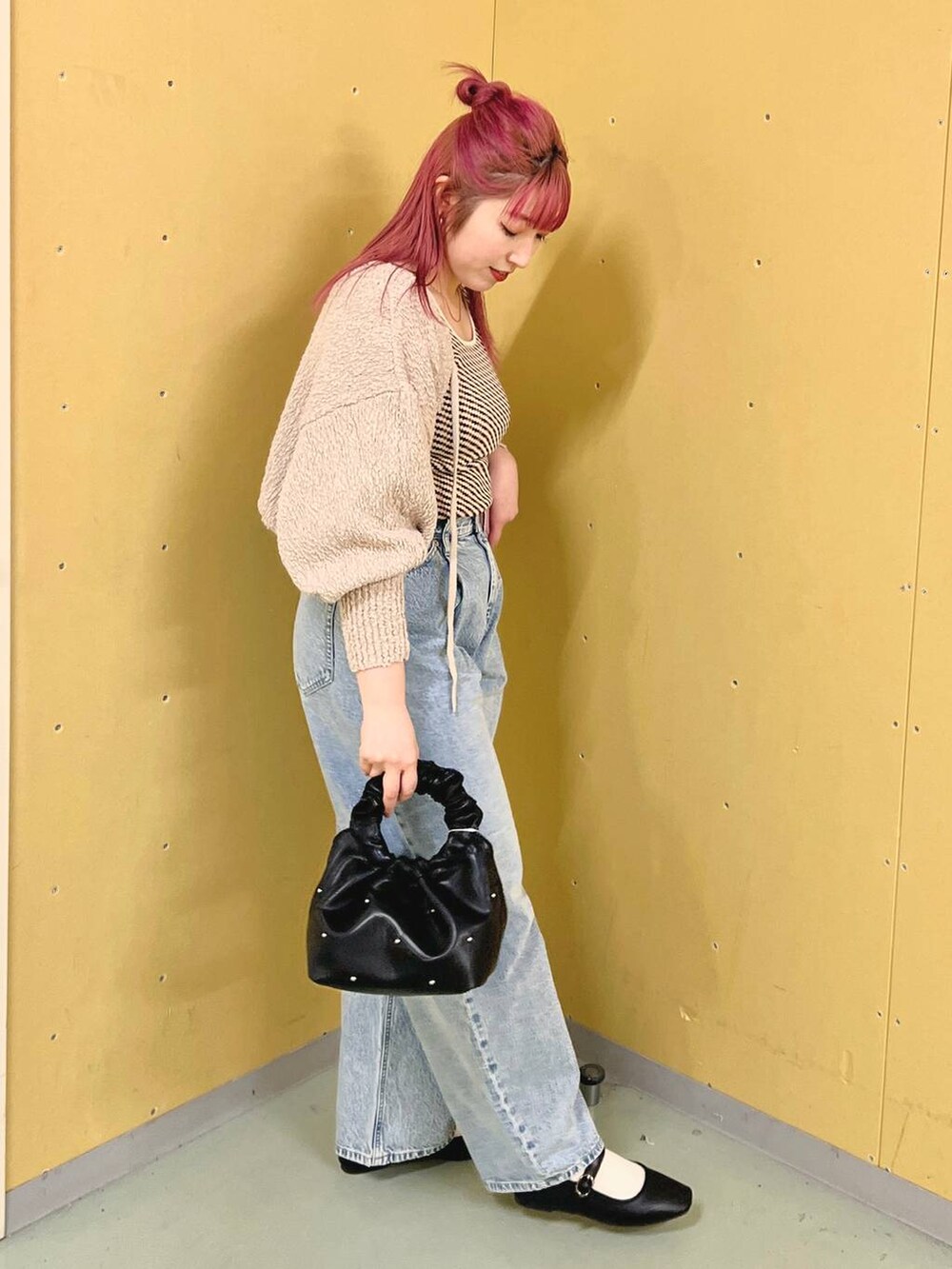 ブラック系のハンドバッグ、ブラック系のパンプス、ブルー系のデニムパンツを着用したレディースの春コーディネートの3枚目の写真
