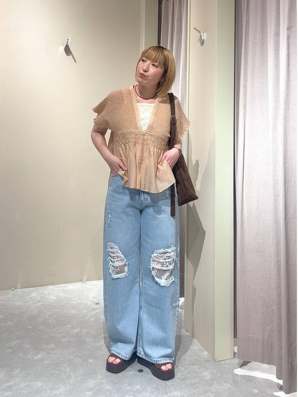 ブラウン系のショルダーバッグ、ブルー系のデニムパンツ、ブラウン系のサンダルを着用したレディースの春コーディネートの7枚目の写真