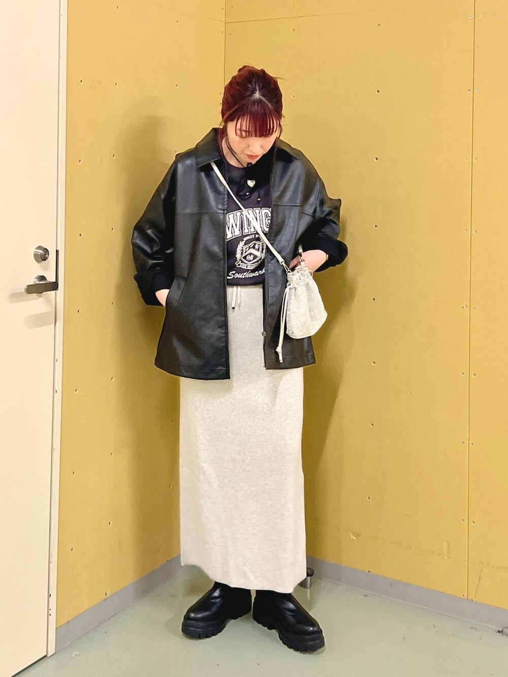 グレー系のスカート、ブラック系のブーツ、シルバー系のショルダーバッグを着用したレディースの秋コーディネートの3枚目の写真