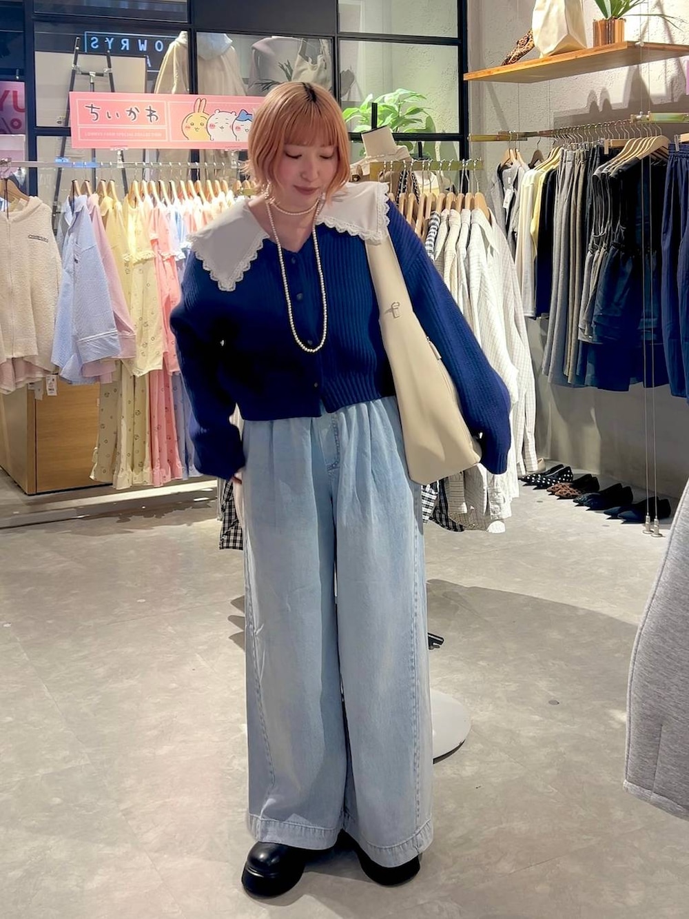 ブラック系のサンダル、ブルー系のデニムパンツ、ホワイト系のショルダーバッグを着用したレディースの冬コーディネートの4枚目の写真