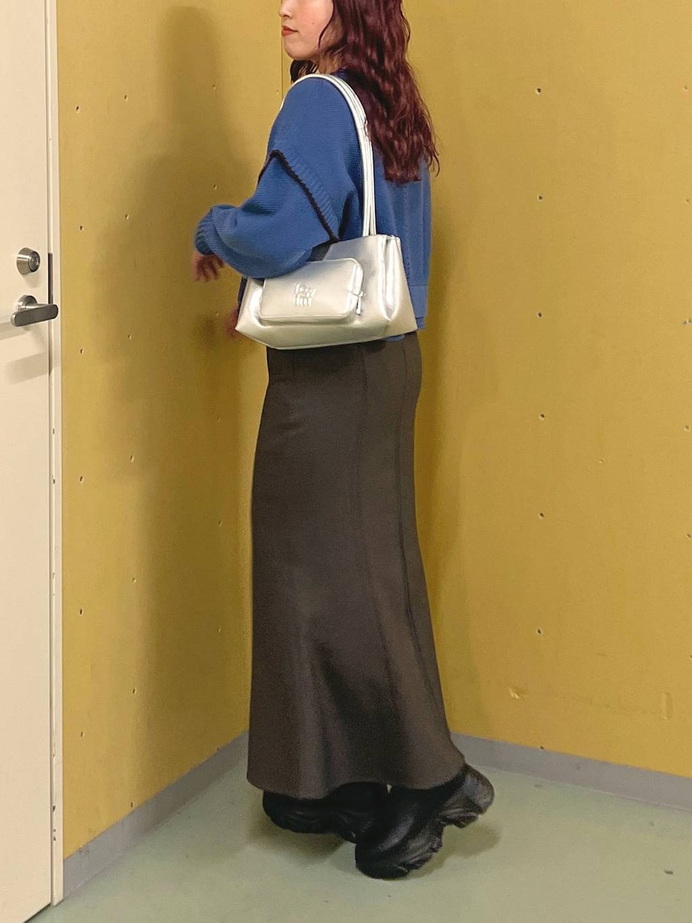 ブルー系のニット/セーター、ブラック系のブーツ、シルバー系のショルダーバッグを着用したレディースの冬コーディネートの2枚目の写真